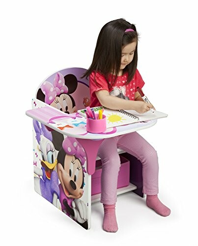 Child sitting at a Minnie Mouse themed desk drawing with crayons.