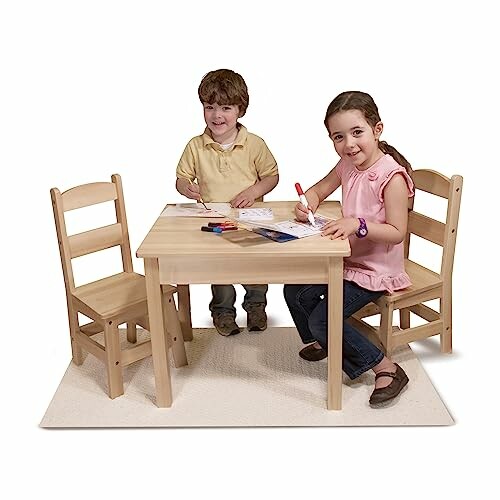 Two children coloring at a small wooden table with chairs.