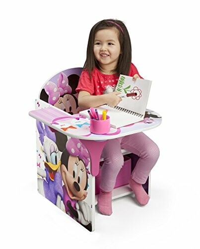 Child sitting at a Minnie Mouse themed desk with coloring book and crayons.