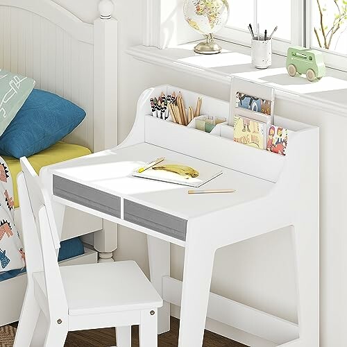 Children's white desk and chair set with books and pencils.