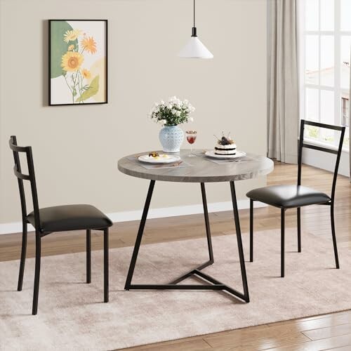 A modern dining room with a round table, two chairs, and wall art.