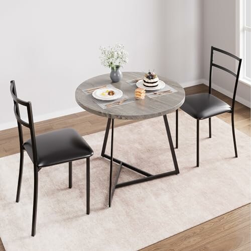 A round dining table with two black chairs on a rug.