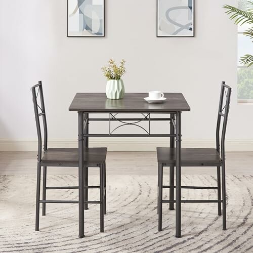 Compact dining table with two chairs, vase, and cup in a modern room.